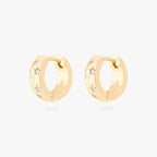 This image displays a pair of 14K gold plated chunky huggies that feature twinkle star shaped engravings with crystal CZ stones throughout the huggies against a white background. 