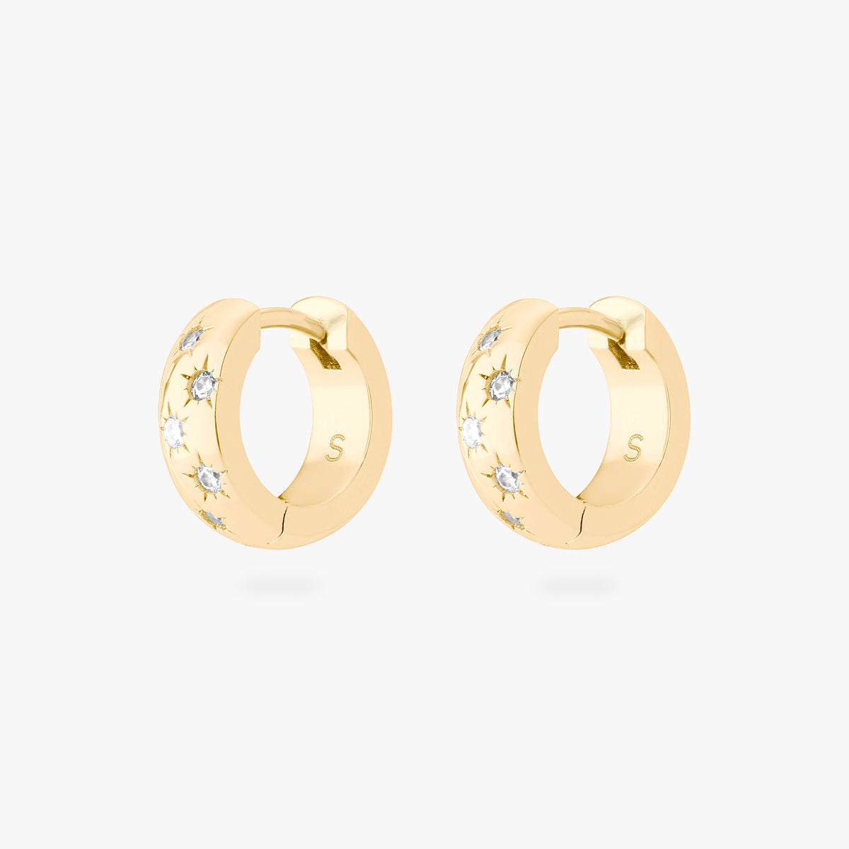 This image displays a pair of 14K gold plated chunky huggies that feature twinkle star shaped engravings with crystal CZ stones throughout the huggies against a white background. 