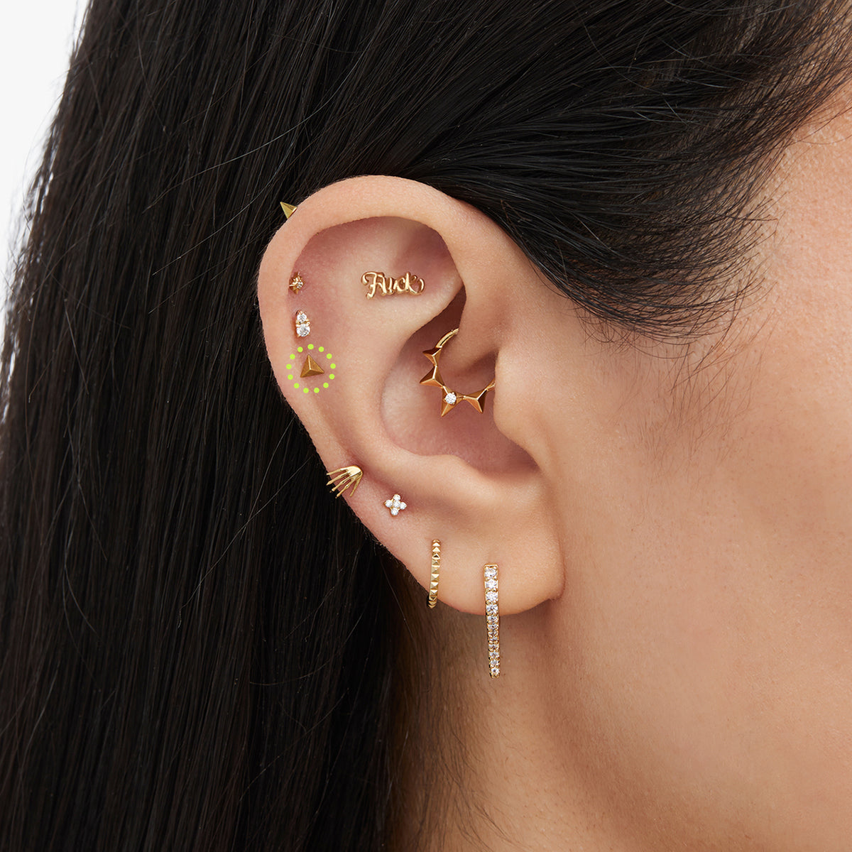 This image is a yellow anodized titanium flatback stud in the shape of a pyramid circled on an ear.