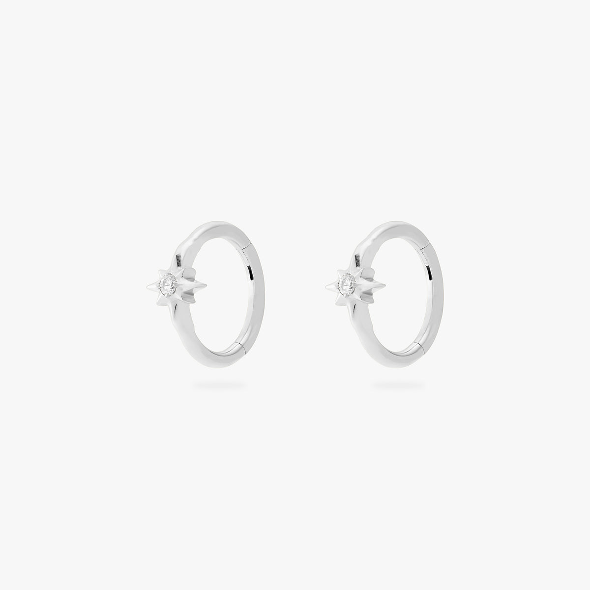 A pair of silver hoop earrings, each with a small star-shaped stone, against a white background.