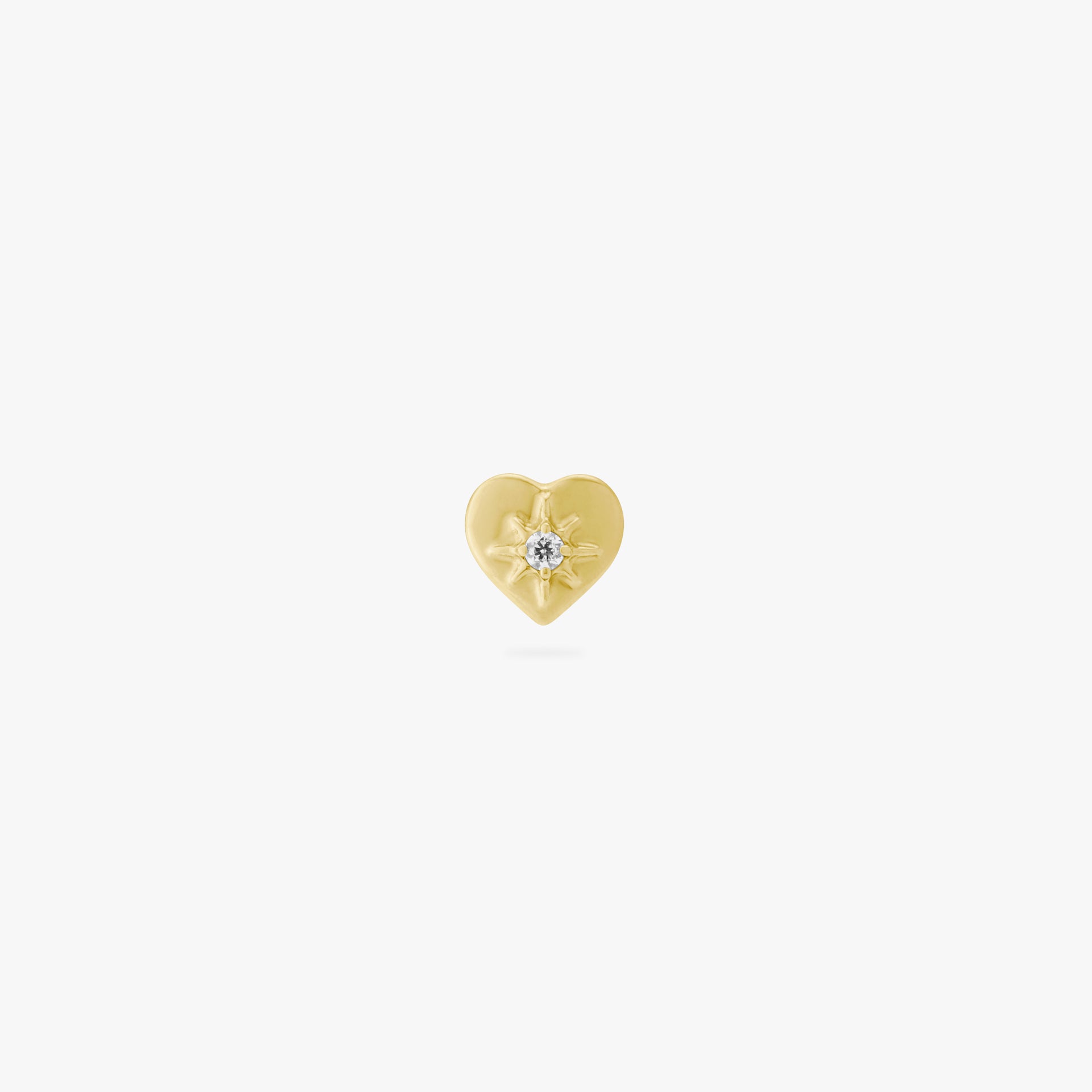 This image is an anodized yellow titanium flatback stud that is heart-shaped with a central twinkle star with a crystal CZ on a white background.