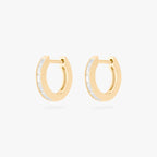 This is an image of a pair of 14K gold plated huggie earrings with 6 baguette cut, bezel set crystal CZs along the edges. 