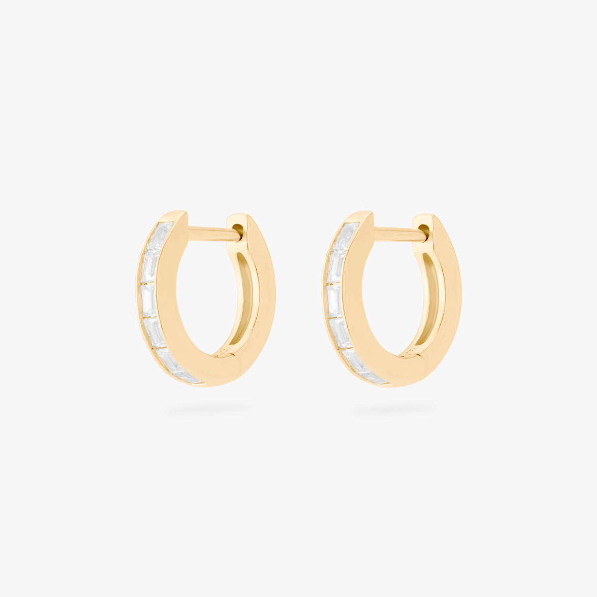 This is an image of a pair of 14K gold plated huggie earrings with 6 baguette cut, bezel set crystal CZs along the edges. 