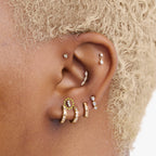 This is an image of a gold-toned titanium flatback stud with 3 micro baguette cut stones placed in a cluster circled on an ear.