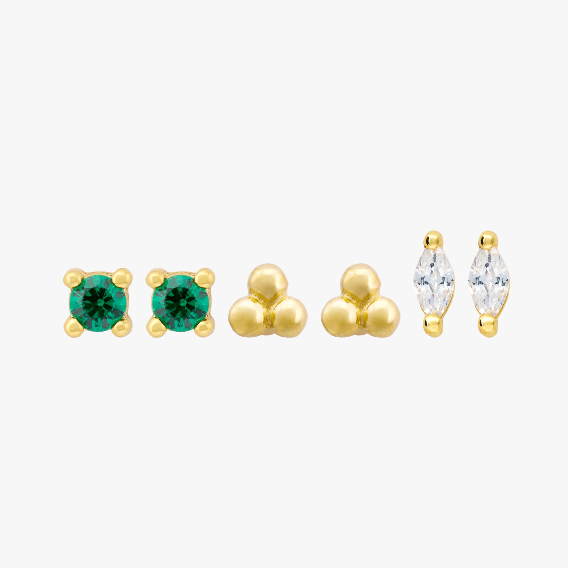 This image shows a set of three pair of 14k Yellow Gold plated flatback studs. The set contains a green cz stone stud, a trinity ball stud and a marquise stud with a clear cz stone.