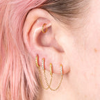 Two separate CZ front huggies attached by a gold chain. 