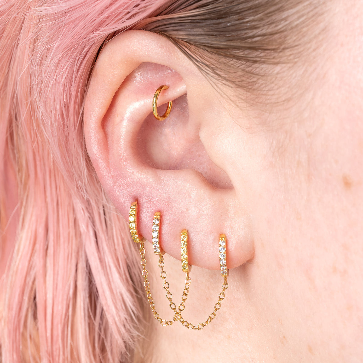 Two separate CZ front huggies attached by a gold chain. 