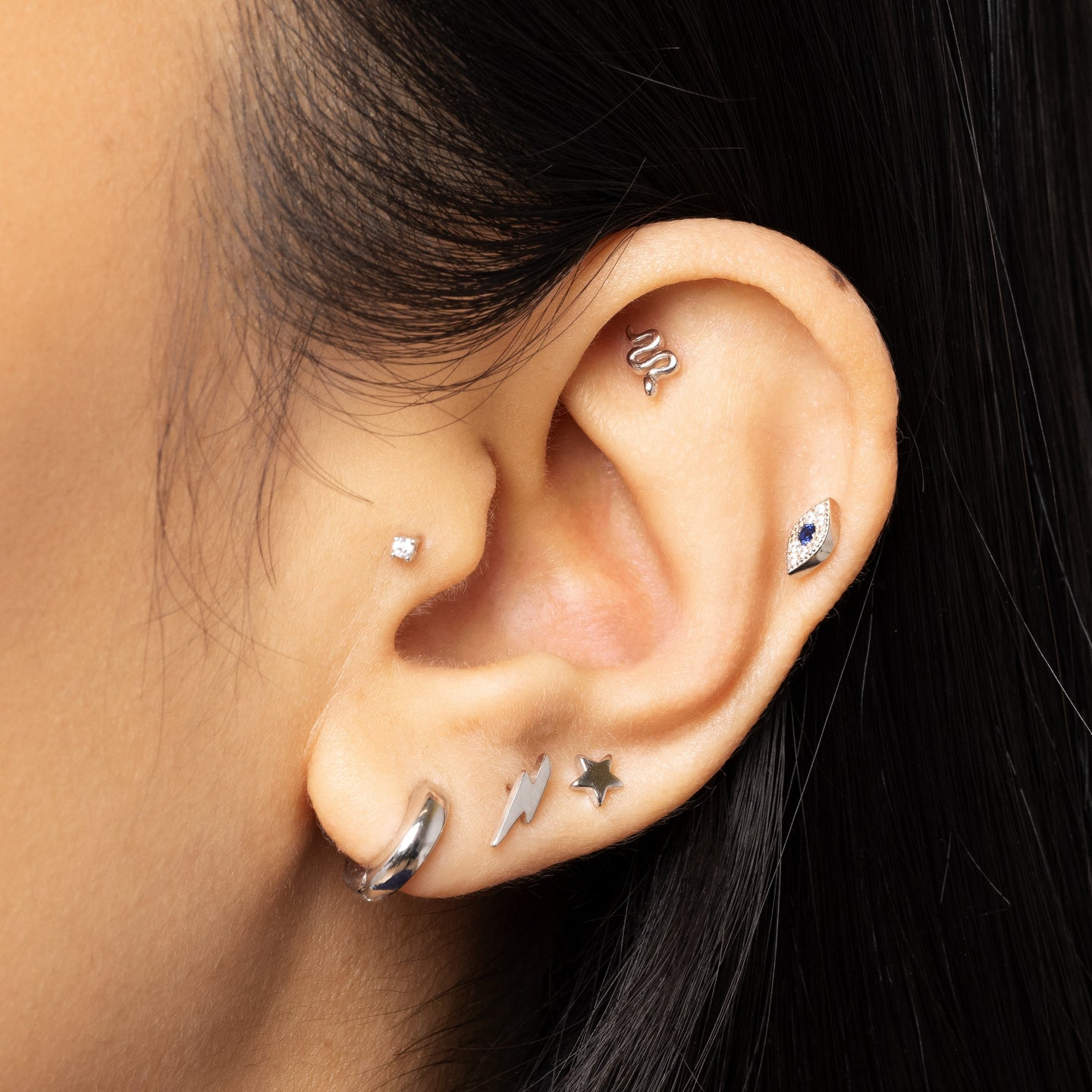 This is a small silver stud that looks like a snake on an ear. [hover] color:silver