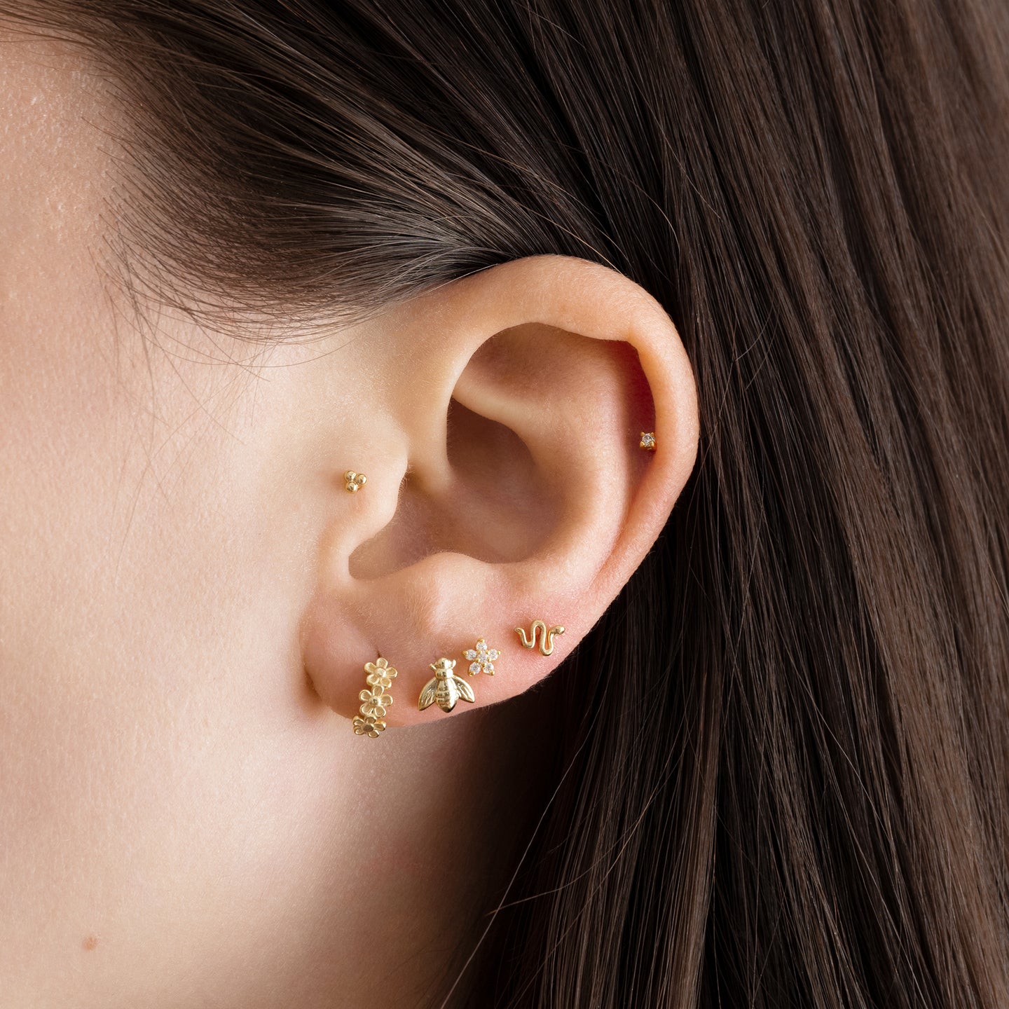 This is a small gold stud that looks like a snake on an ear. [hover] color:null|gold