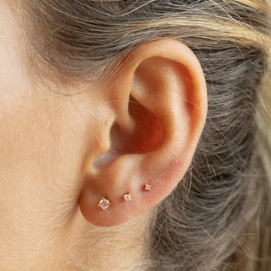 This is a set of gold studs that includes a pair of small cz studs, a pair of mini cz studs, and a pair of micro cz studs. [hover] color:null|gold/clear