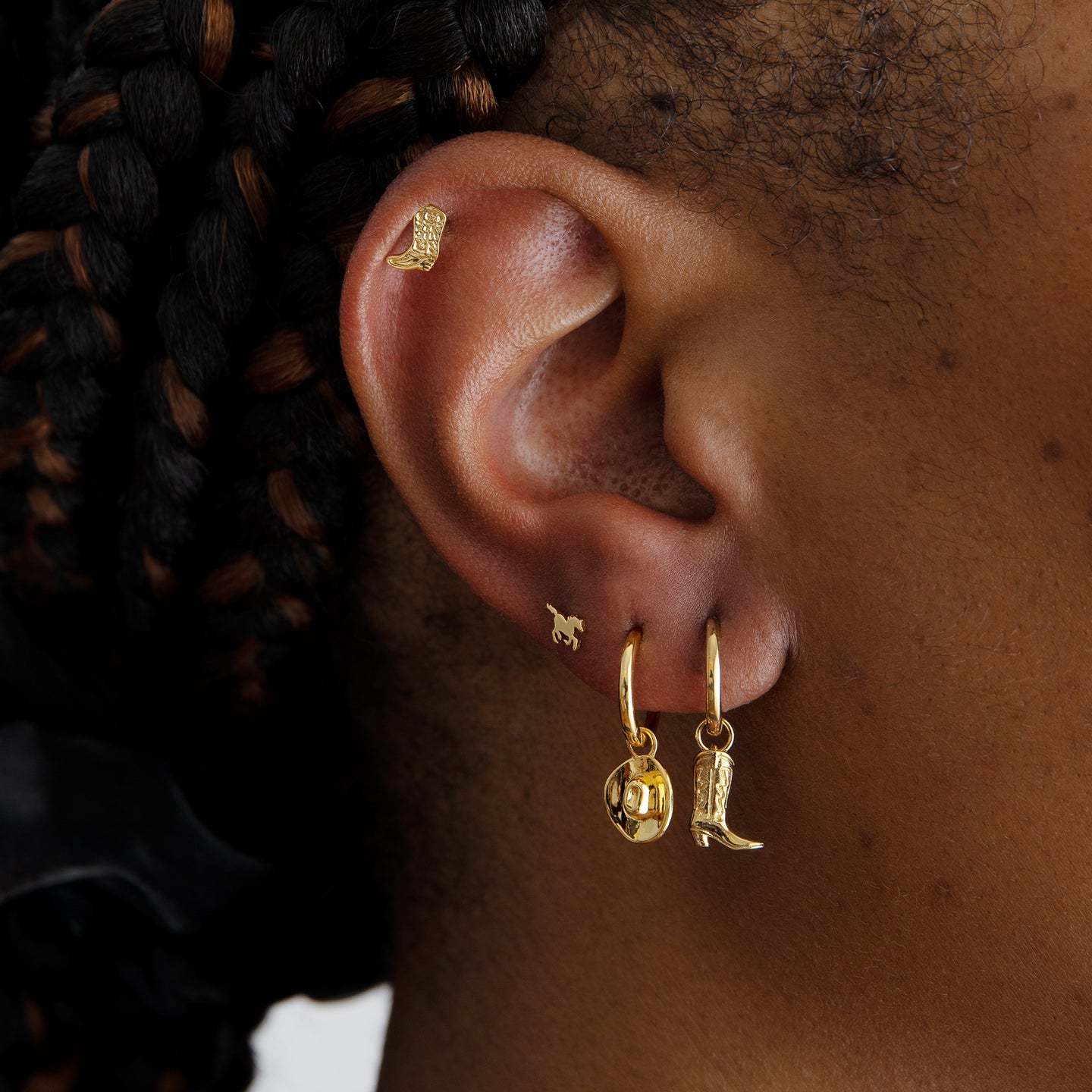 This is a small gold cowboy boot shaped stud with detailing [hover] color:null|gold