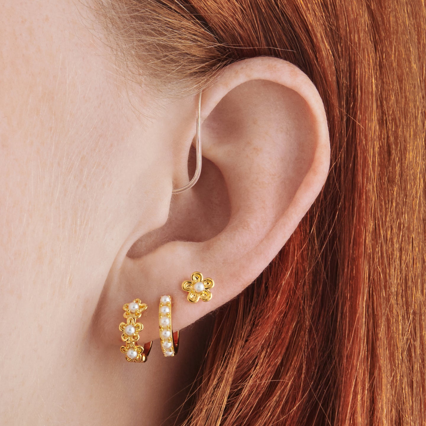 set consisting of two gold pearl daisy huggies and a gold pearl huggie and a gold pearl daisy stud on ear [hover] color:null|gold