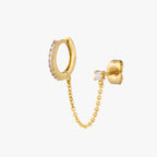 Chained gold huggie with cubic zirconia and gold stud with cubic zirconia on an ear. 