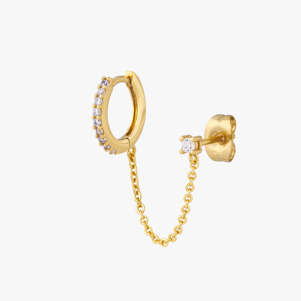 Chained gold huggie with cubic zirconia and gold stud with cubic zirconia on an ear. 