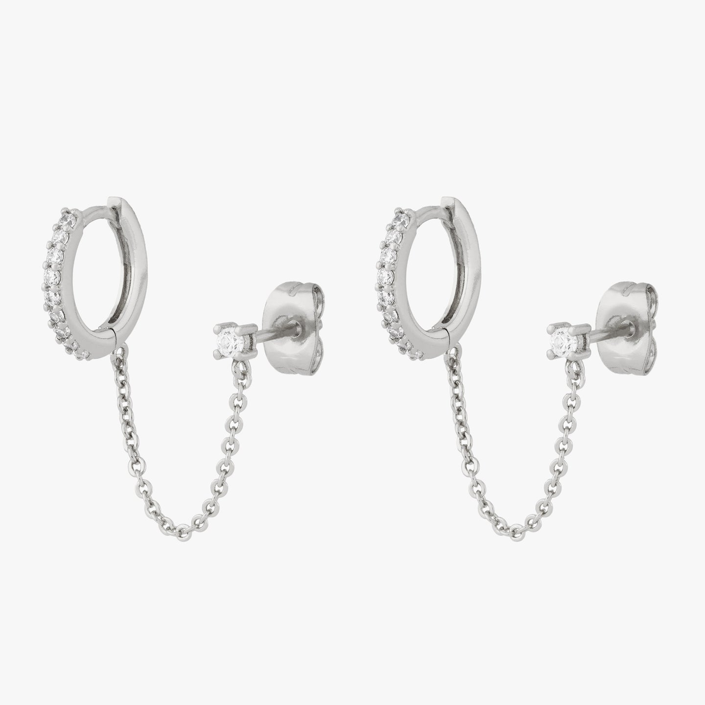 Chained silver huggie with cubic zirconia and silver stud with cubic zirconia on an ear. [pair] color:null|silver/clear