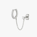 Chained silver huggie with cubic zirconia and silver stud with cubic zirconia on an ear. color:null|silver/clear