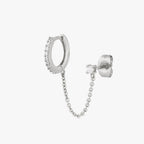 Chained silver huggie with cubic zirconia and silver stud with cubic zirconia on an ear. color:null|silver/clear
