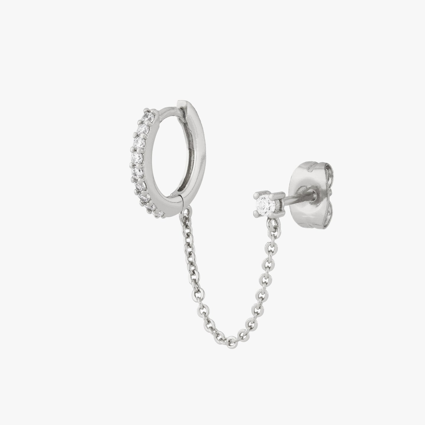 Chained silver huggie with cubic zirconia and silver stud with cubic zirconia on an ear. color:null|silver/clear