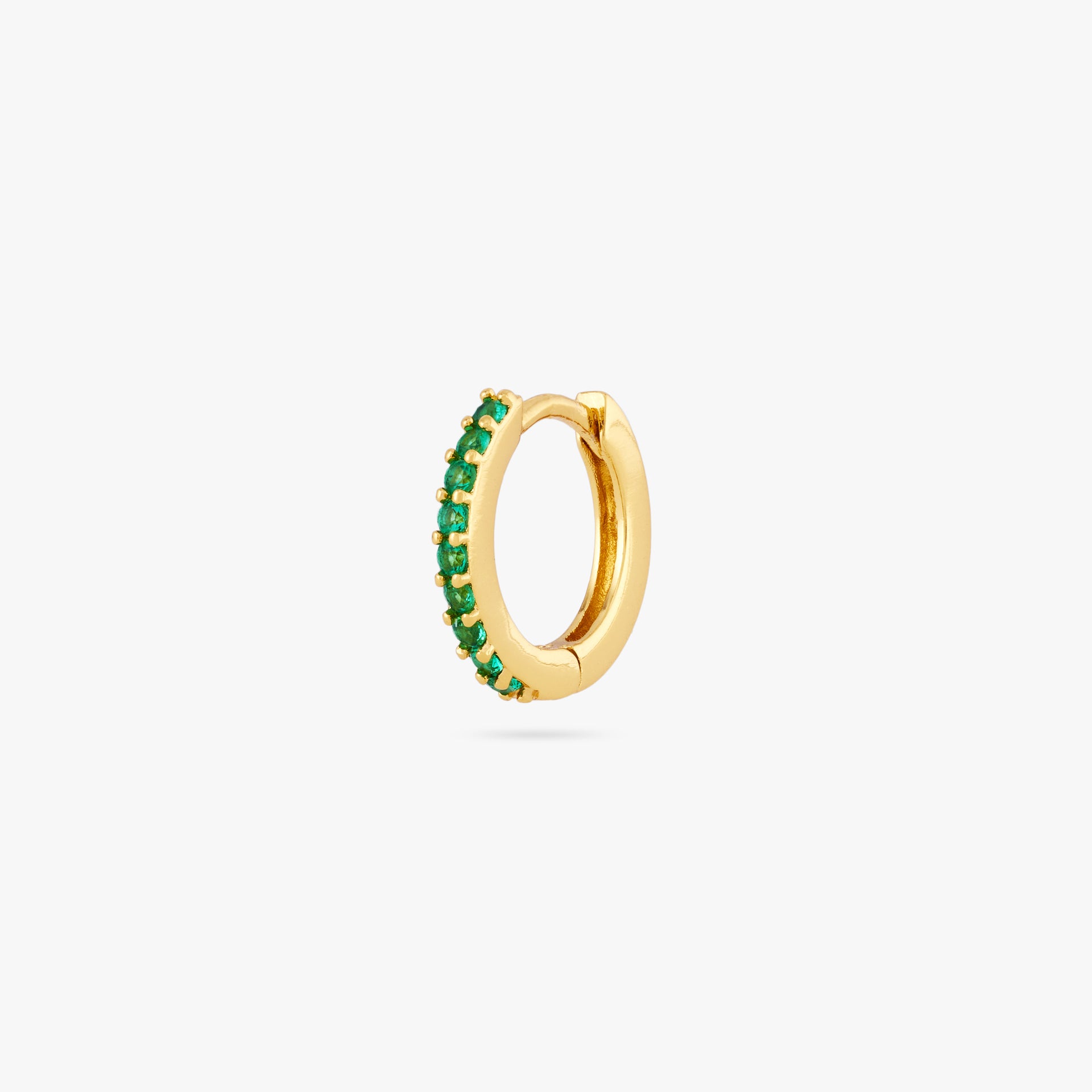 A mini gold huggie lined with green cz gems on the front - Main view