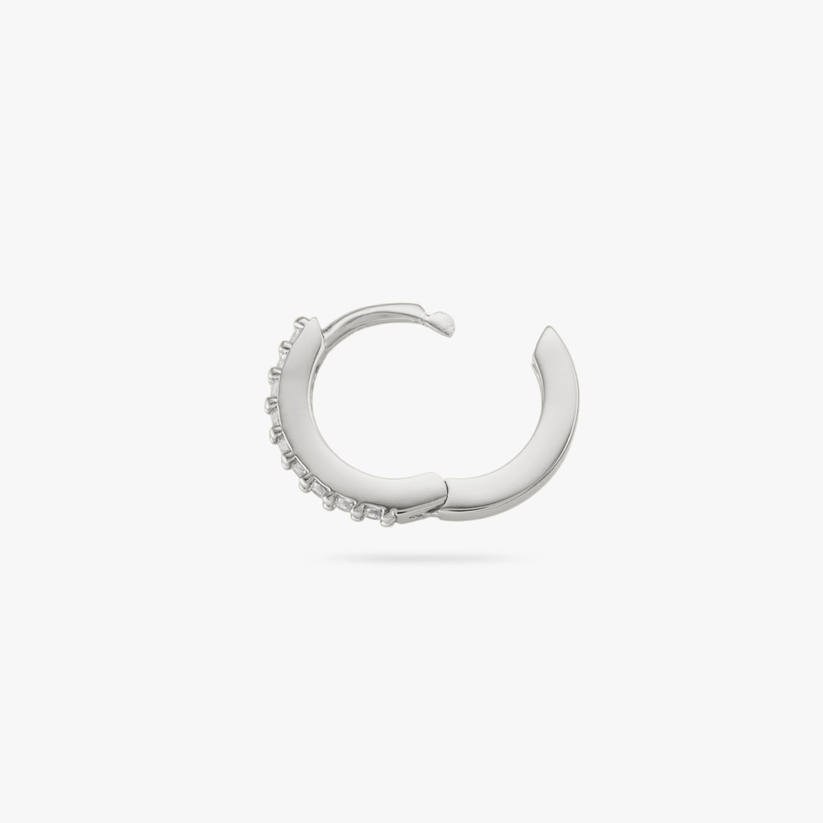 A mini silver huggie lined with clear cz gems on the front and its clasp undone color:null|silver/clear