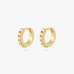 This is a pair of small gold huggies that have small pearls lining the front of them [pair] color:null|gold