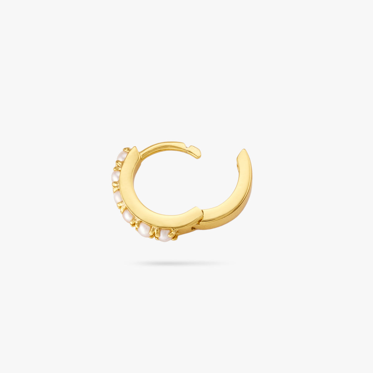 This is a small gold huggie that has small pearls lining the front of it and the clasp is undone color:null|gold