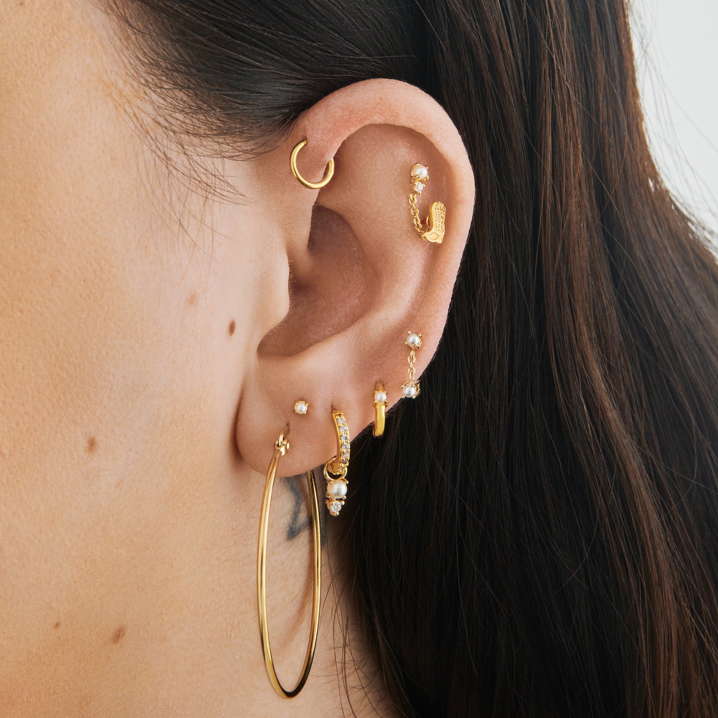 a mini pave huggie in gold/clear with a charm that has a stacked pearl and clear cz on ear [hover] color:null|gold/pearl