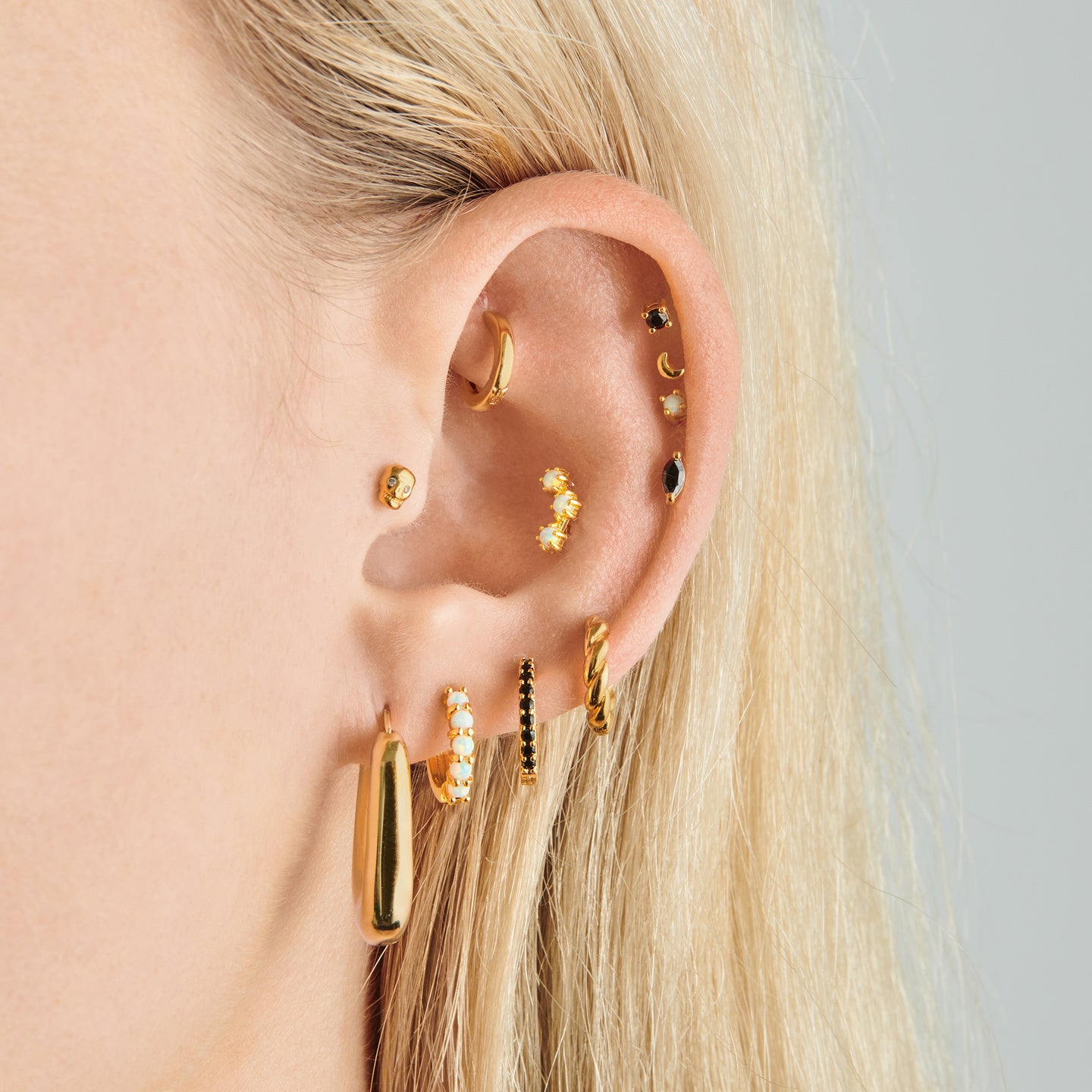 a gold micro helix huggie with a clear bezel on ear [hover] color:null|gold/clear