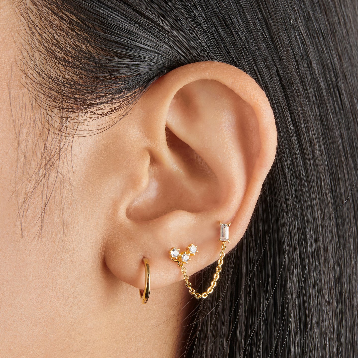 Gold slim huggies, a 30mm gold chain, a baguette stud, and a cz cluster stud [hover] color:null|gold