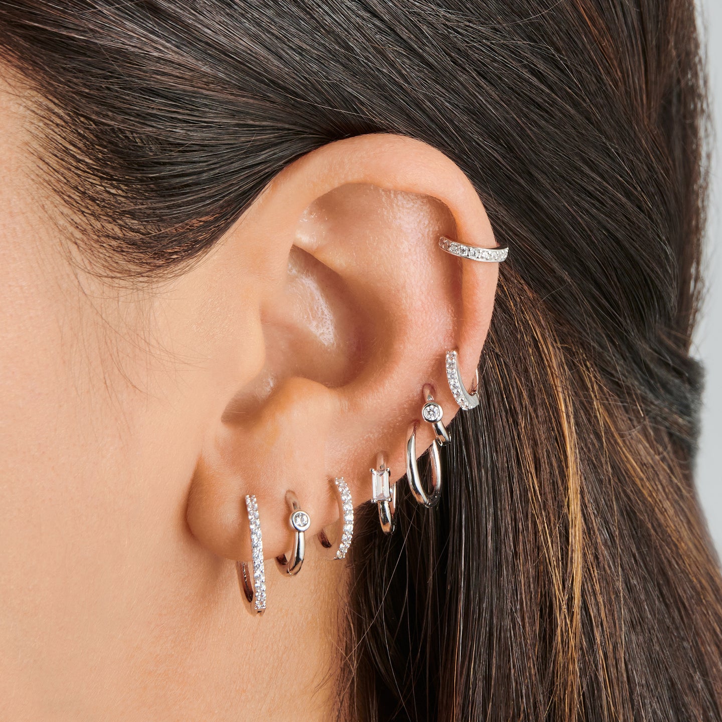 a silver micro helix huggie with a clear bezel on ear [hover] color:null|silver/clear