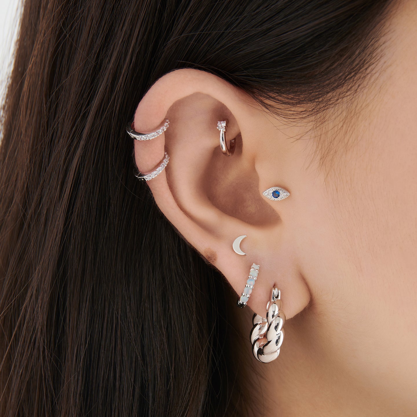 This is a twisted croissant-like silver hoop on ear [hover] color:null|silver