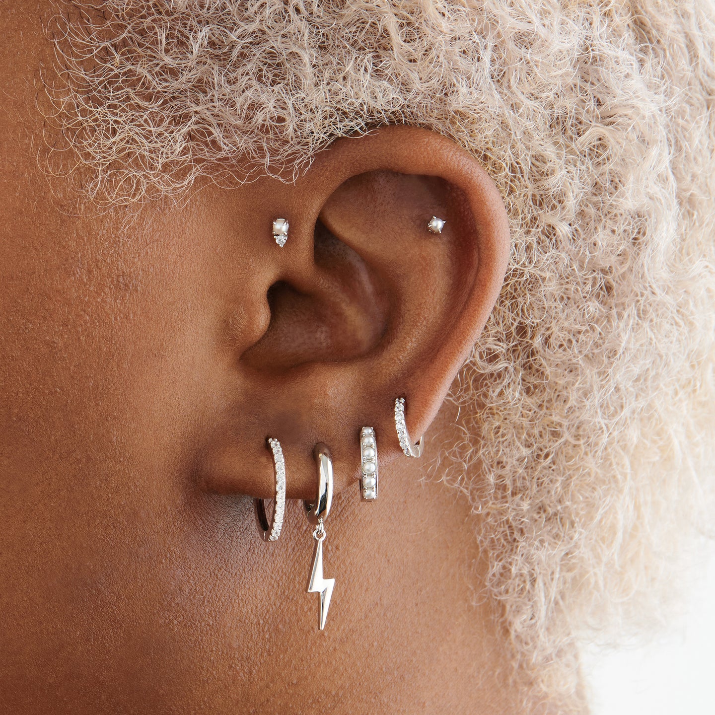 This is a small silver stud with a pearl accent on ear [hover] color:null|silver