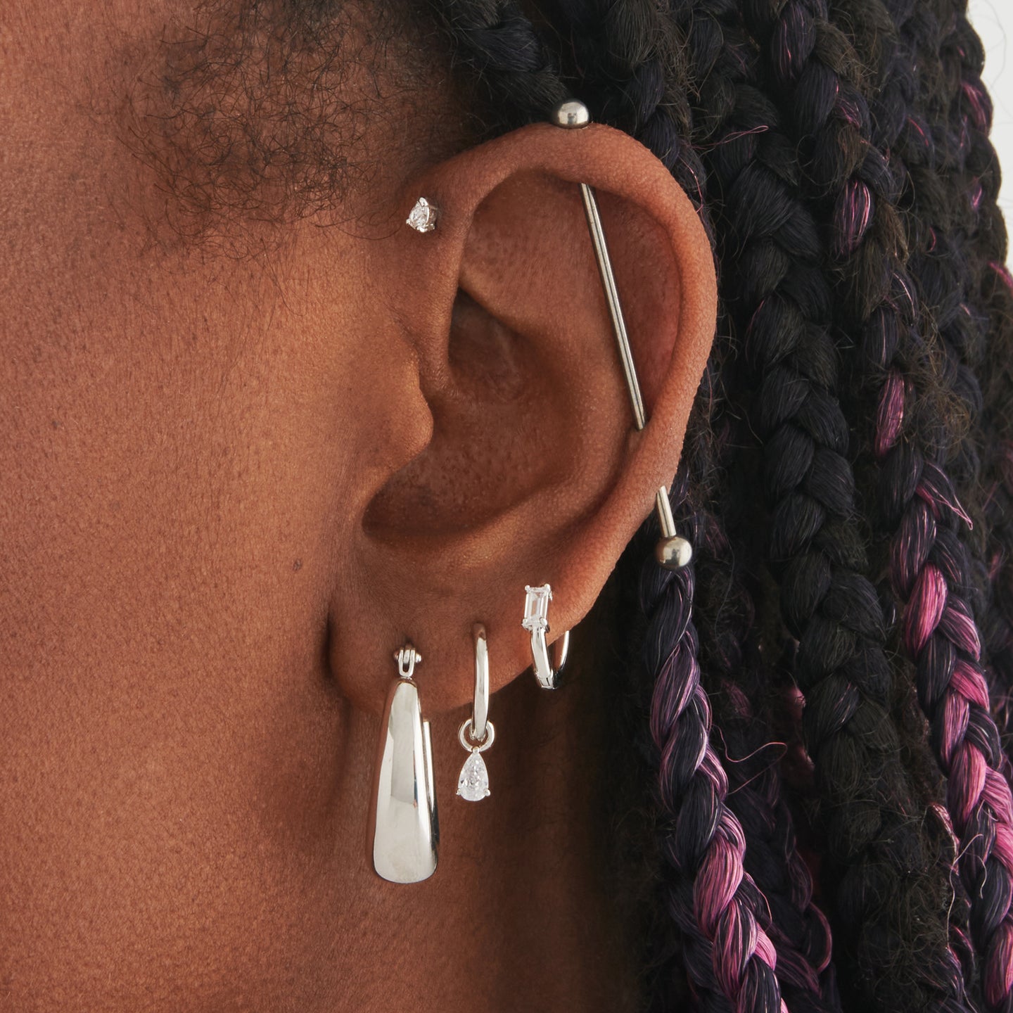 an oval shaped hoop earring in silver on ear [hover] color:null|silver