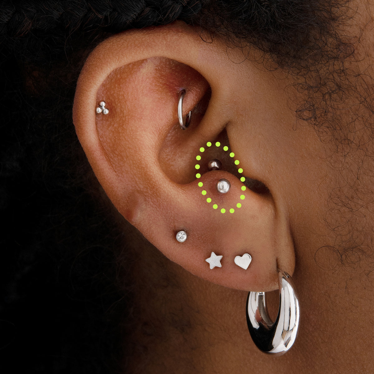 This is an image of a silver-toned titanium curved barbell that is 8mm in length circled on an ear. - Alternative view 1