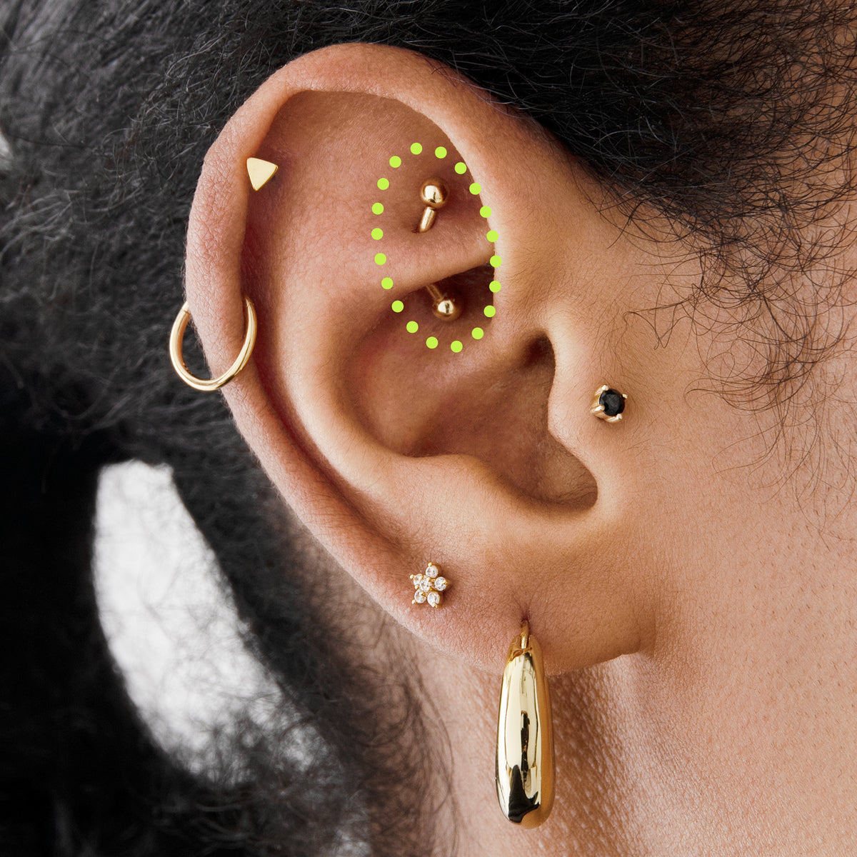 This is an image of a 14K gold curved barbell that is 8mm in length circled on an ear.