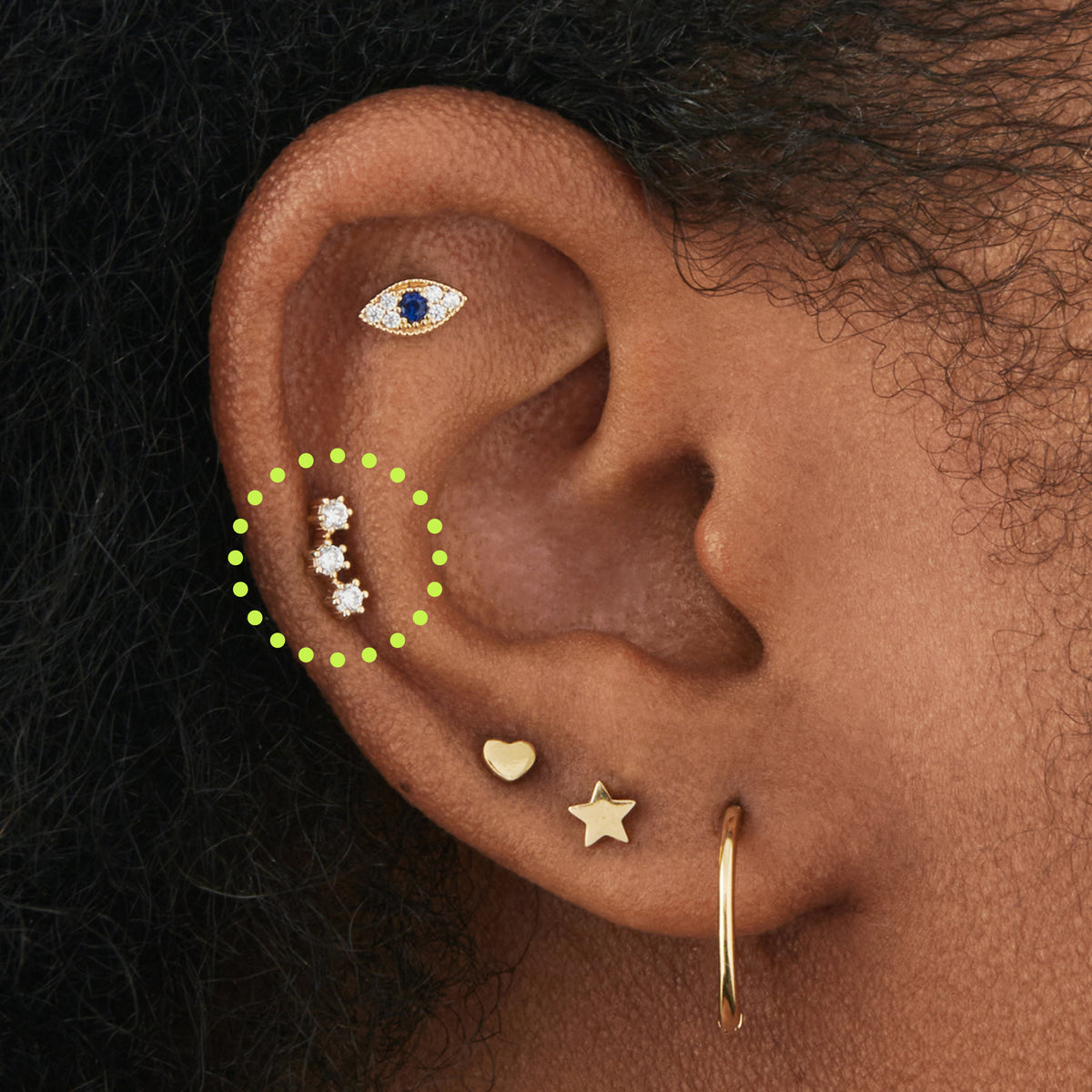 This image is a 14K gold flatback stud that features 3 crystal CZs in a cluster shape circled on an ear.