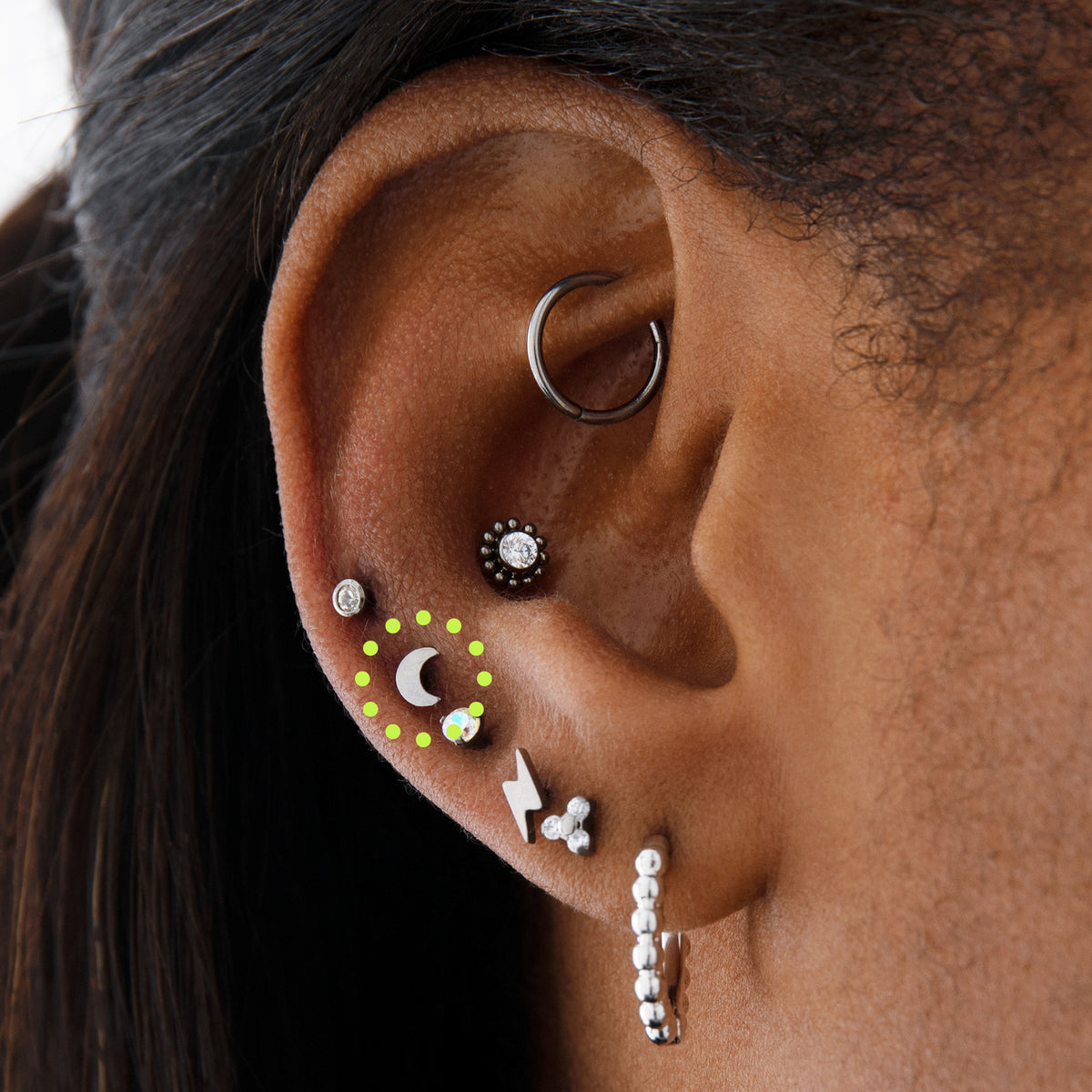 This image is a silver toned titanium crescent moon shaped flatback stud circled on an ear.