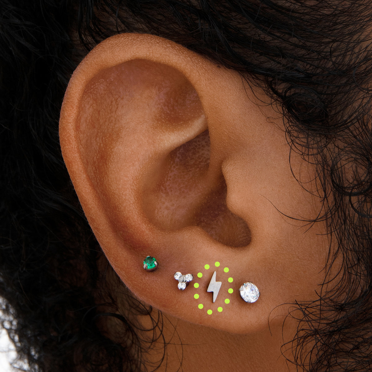 This image is a silver-toned titanium lightning bolt-shaped stud circled on an ear.