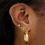 This image is a 14K gold ball-shaped flatback stud circled on an ear.