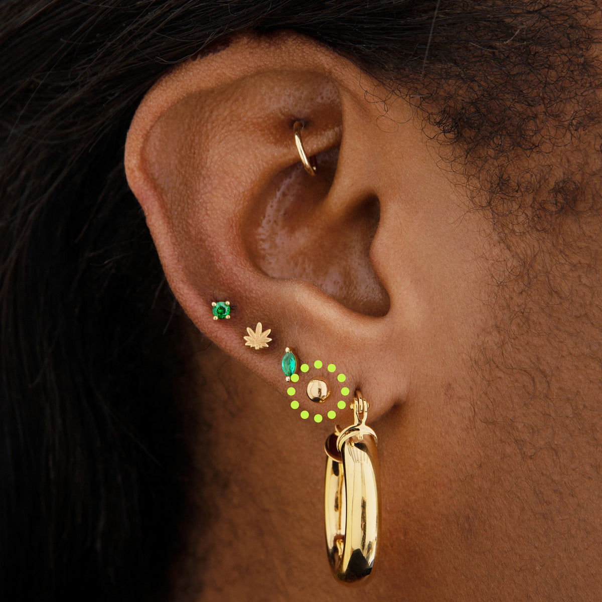 This image is a 14K gold ball-shaped flatback stud circled on an ear.