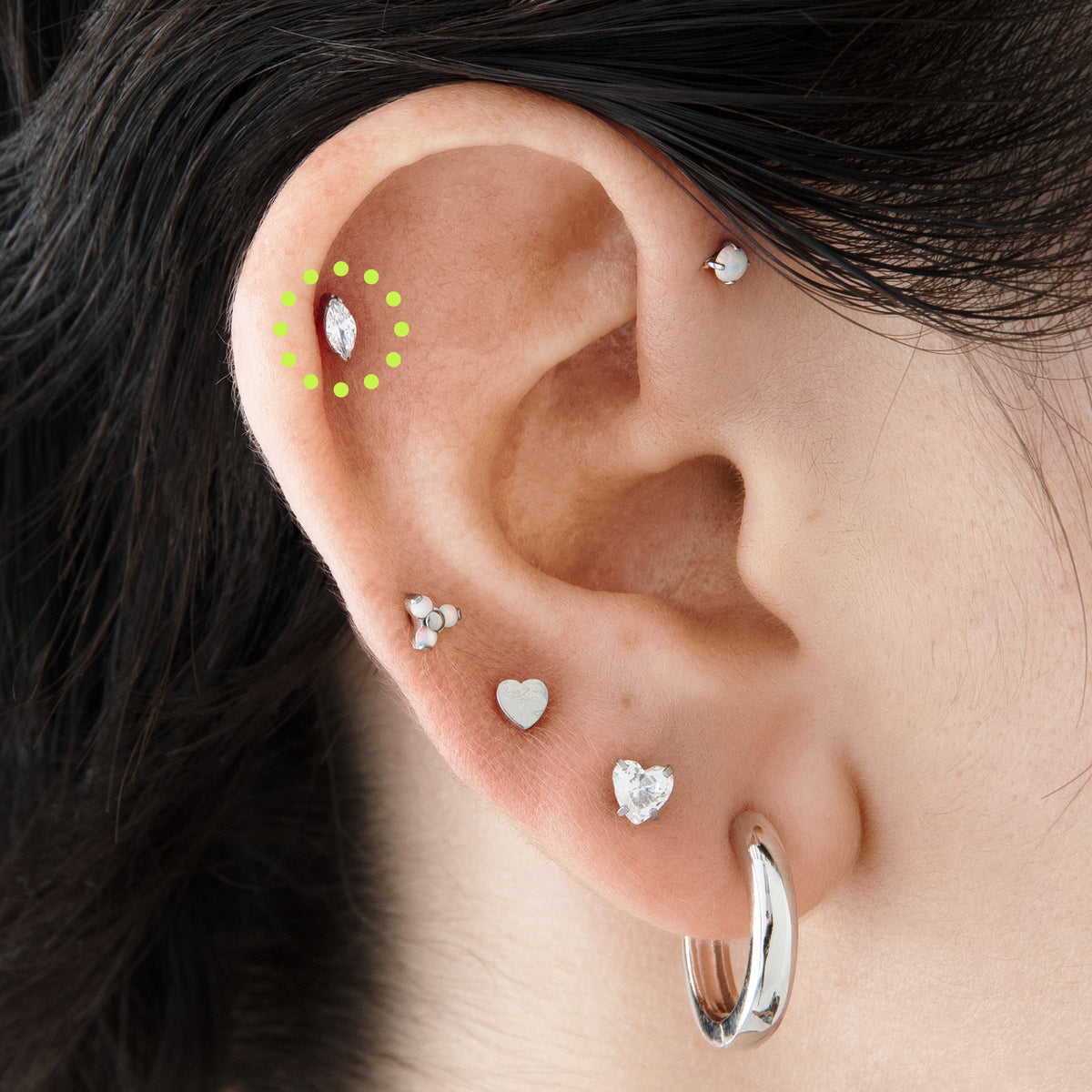 This image is a silver toned titanium flatback stud with a marquise set crystal CZ stone circled on an ear. - Alternative view 1