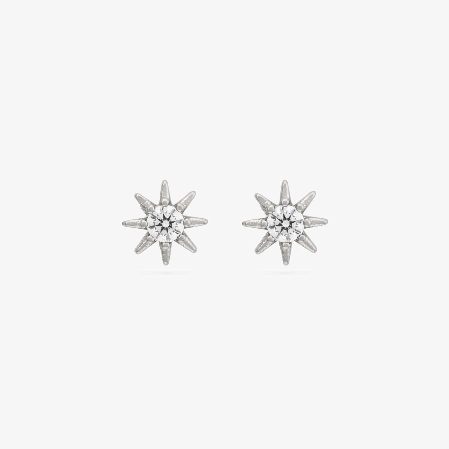 A pair of silver circular shaped studs with very small spikes all around it and CZ gem in the center. [pair] color:null|silver/clear