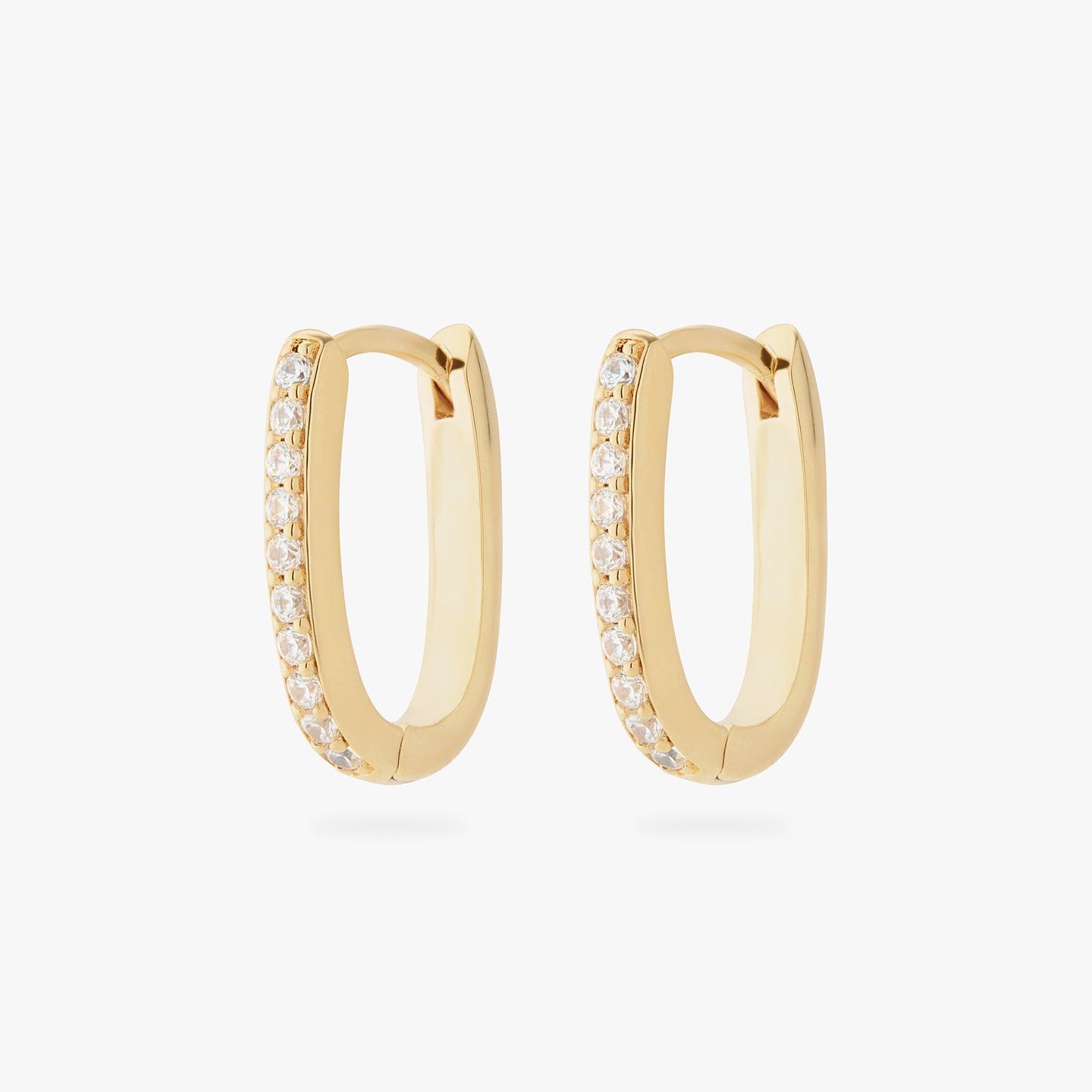 a pair of gold medium oval hoops that have one side pave [pair] color:null|gold/clear