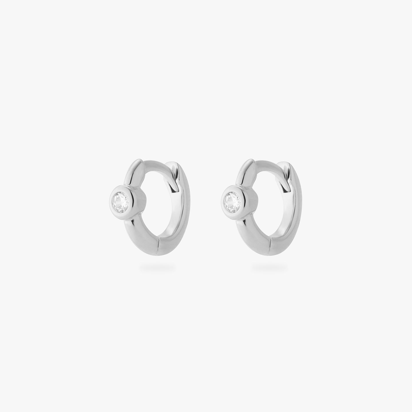 a pair of silver micro helix huggies with a clear bezel [pair] color:null|silver/clear