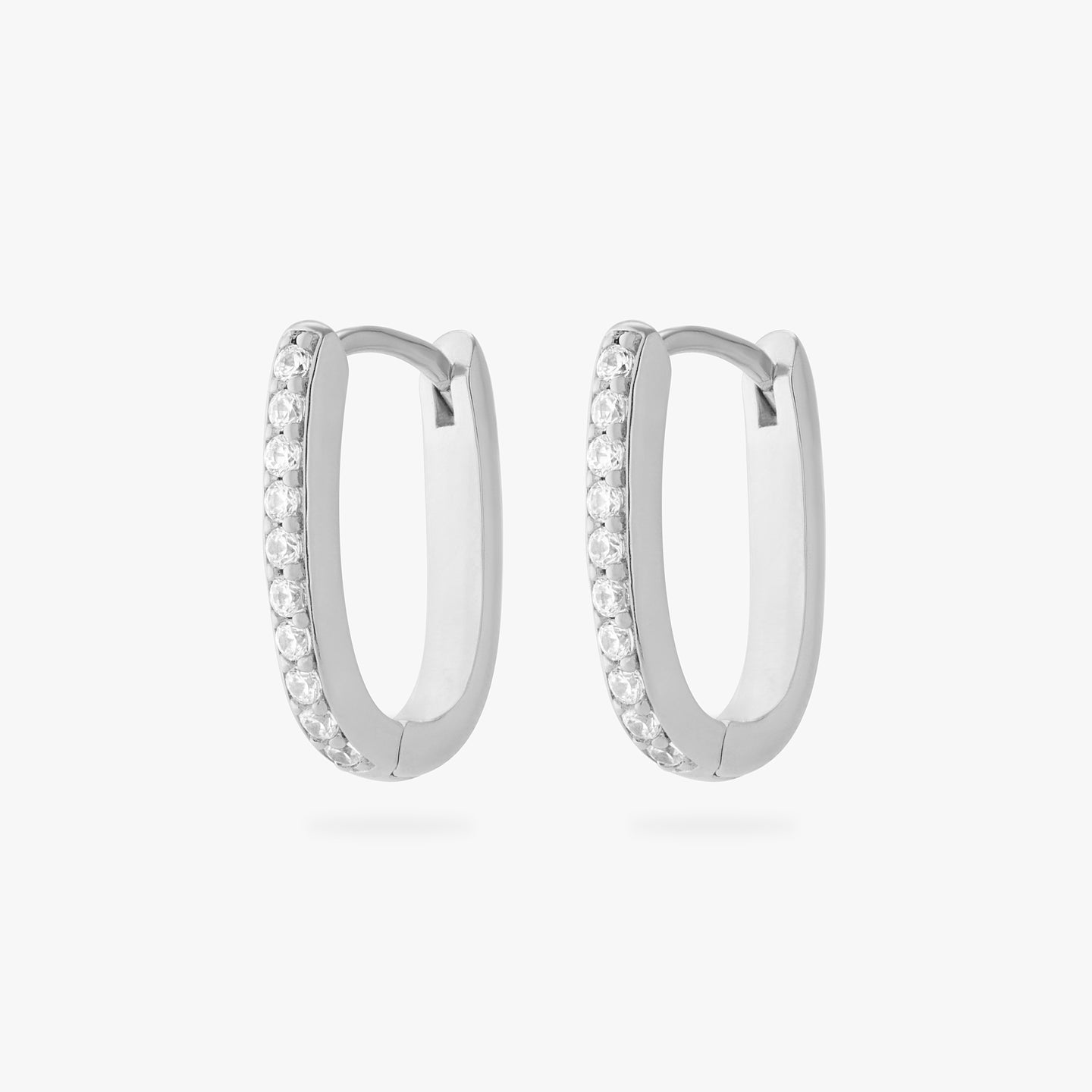 a pair of silver medium oval hoop that have one side pave [pair] color:null|silver/clear