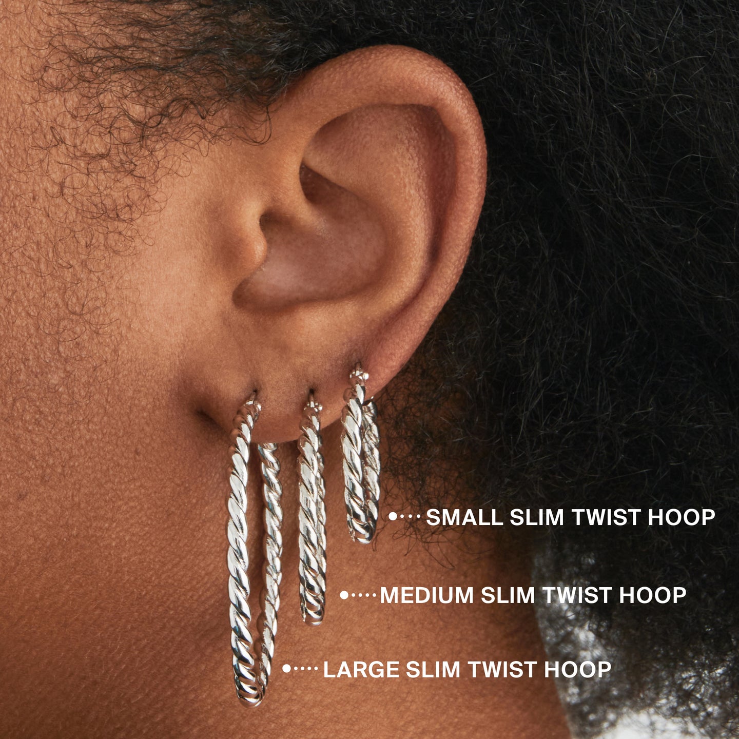 a small slim silver twisted hoop earring on ear [hover] color:null|silver